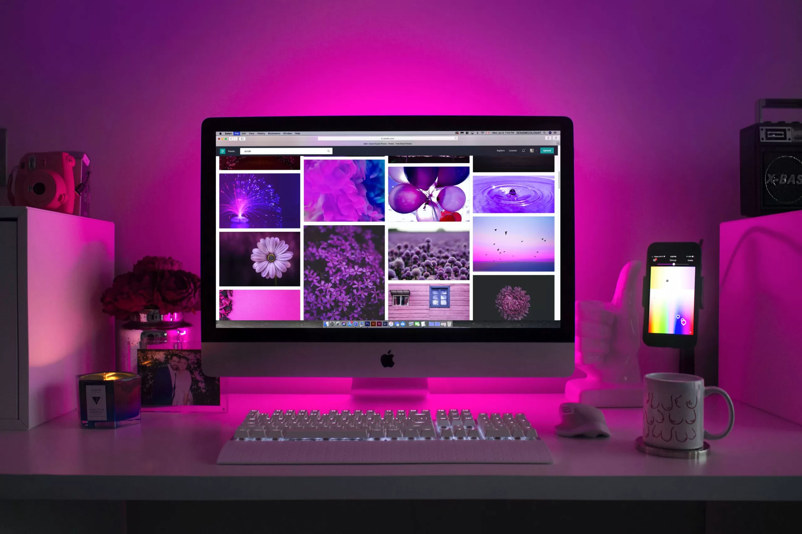 A desk with purple lights and a Laptop and web page design