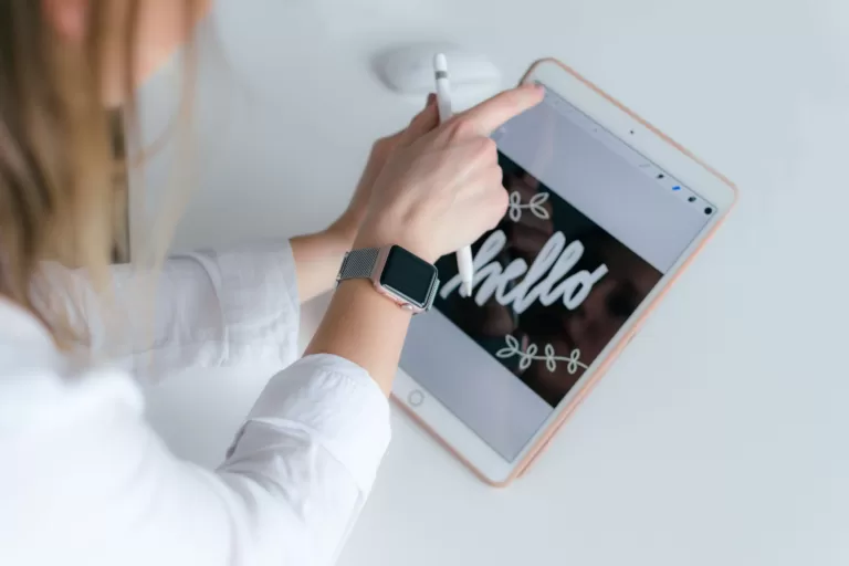 A young woman is holding a Tablet with her left hand and searching for an App with her right hand.
